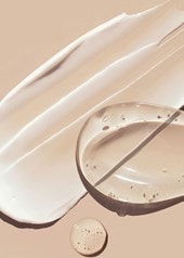 Etwas durchsichtiges Serum und etwas weiße Creme auf einem beigefarbenen Untergrund