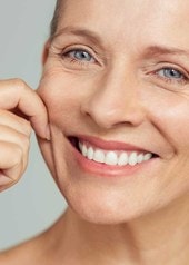 Ältere Frau zieht sanft an ihrer Gesichtshaut