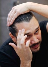 Mann betrachtet im Spiegel seinen Haaransatz und prüft möglichen Haarausfall im Badezimmer