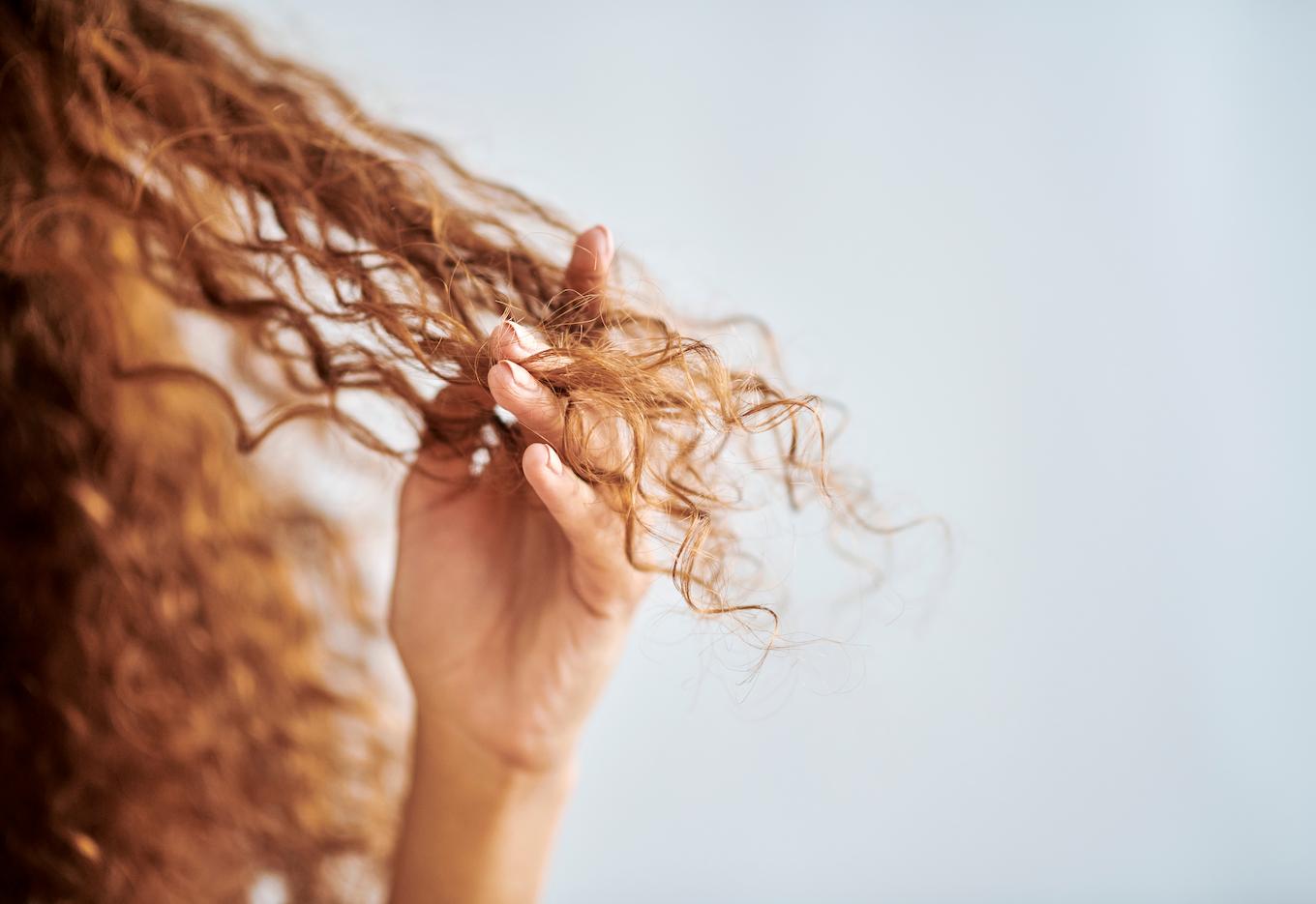 Lockiges rotes Haar, das mit den Fingern gehalten wird