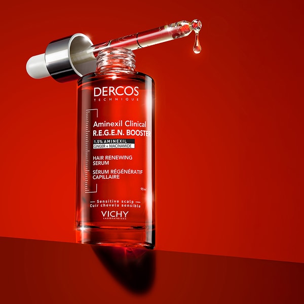 DERCOS Aminexil Clinical Haarserum von Vichy mit Pipette vor rotem Hintergrund