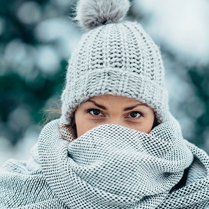Frau mit Strickmütze und Schal im Schnee, nur die Augen sichtbar 