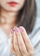 Frau hält einen Büschel Haare zwischen den Fingern