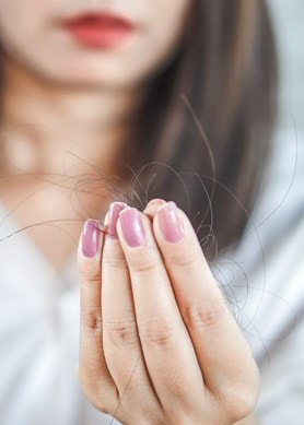 Frau hält einen Büschel Haare zwischen den Fingern