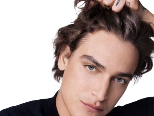 Nahaufnahme eines dunkelhaarigen,männlichen Models mit mittelkurzen Haaren, das sich in die Haare greift