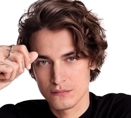 Nahaufnahme eines dunkelhaarigen,männlichen Models mit mittelkurzen Haaren, das sich in die Haare greift