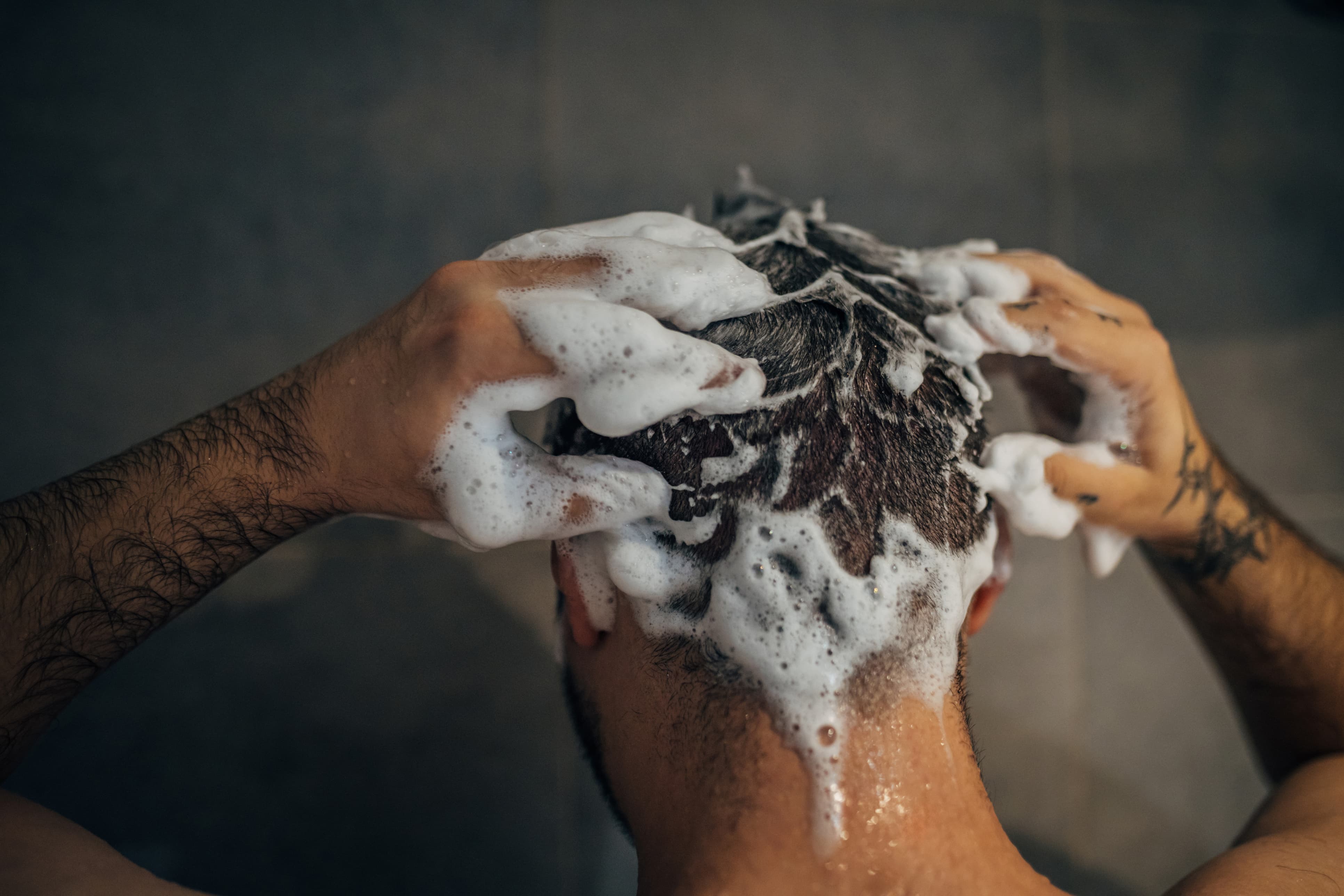 Mann wäscht sich die Haare mit Shampoo, Schaum bedeckt den Kopf