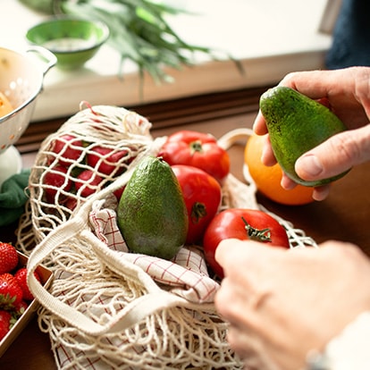 Frisches Obst und Gemüse mit Erdbeeren, Orangen, Avocados und Tomaten auf einem Küchentisch