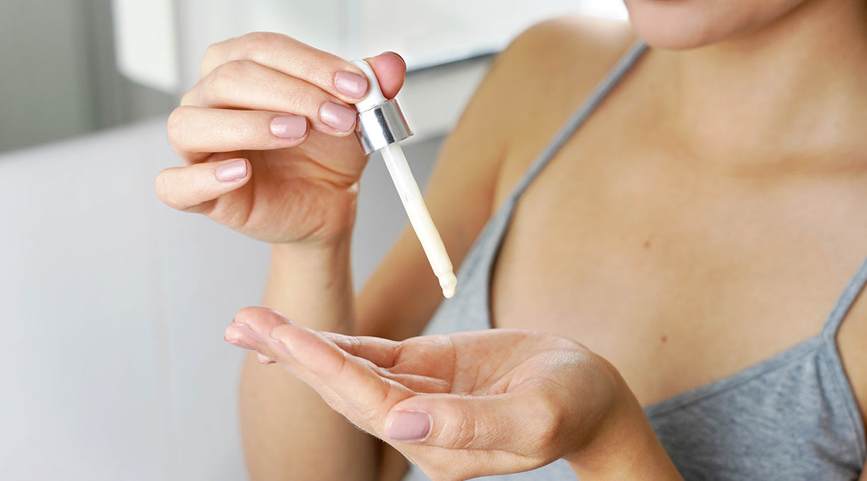 Eine Frau gibt sich Niacinamid-Serum auf die Hände