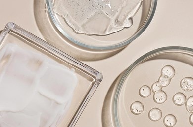 Transparente Kosmetiktexturen und Cremes in Glasschalen auf hellem Hintergrund