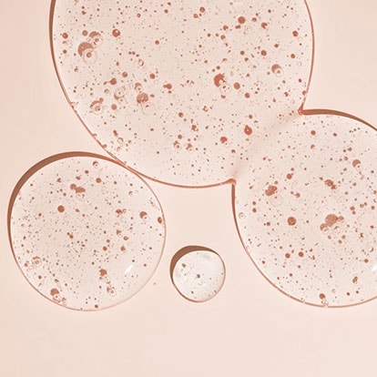 Ein paar Tropfen Squalan auf einem apricotfarbenen Untergrund