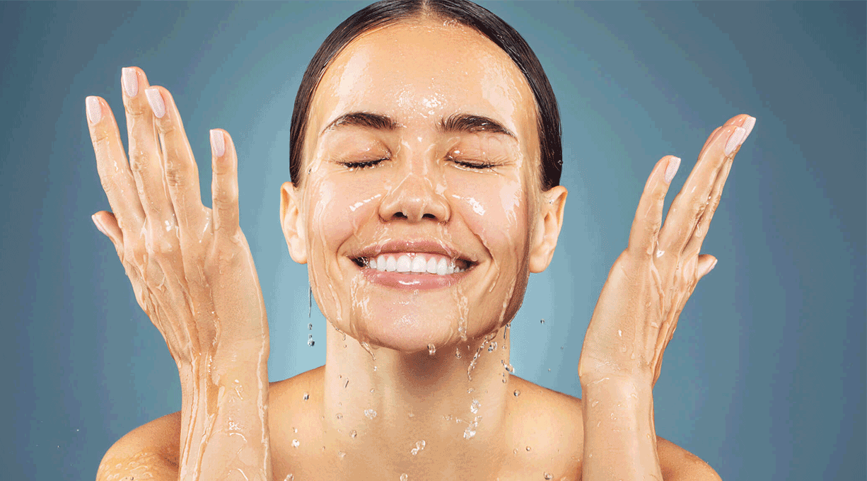 Gepflegte, lächelnde Haut erfrischt sich mit Wasser im Gesicht