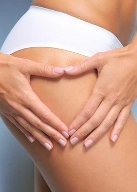 Eine Frau die mit ihren Händen ein Herz formt und an ihren Oberschenkel hält