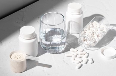 Verschiedene Nahrungsergänzungsmittel wie Kollagen, Tabletten und ein Glas wasser stehen auf einem Tisch