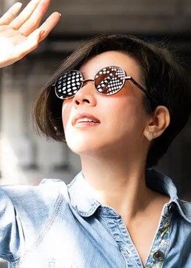 Eine Frau mit Sonnenbrille schaut Richtung Sonne