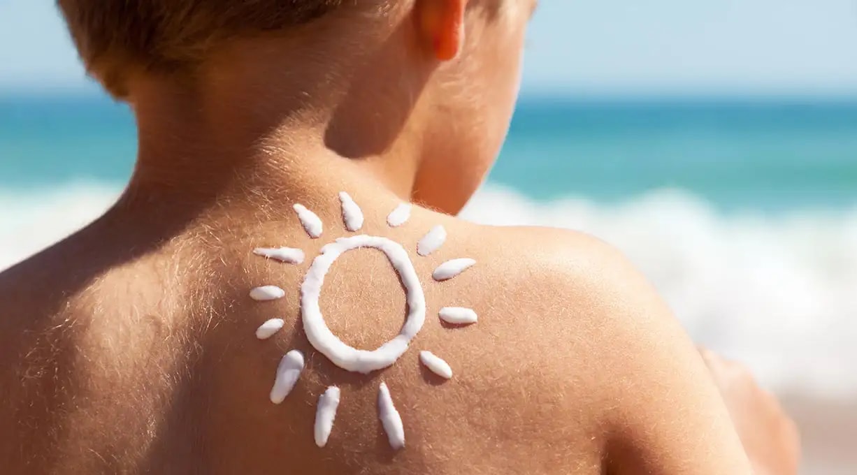 Aufnahme des Rücken eines Kindes auf dessen Schulter eine Sonne mit Sonnencreme gemalt wurde.