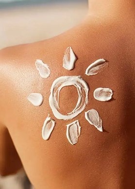 Aufnahme des oberen Rücken einer Frau, auf dessen linken schulter eine Sonne mit Sonnencreme gemalt