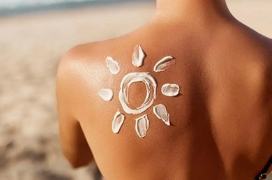 Aufnahme des oberen Rücken einer Frau, auf dessen linken schulter eine Sonne mit Sonnencreme gemalt