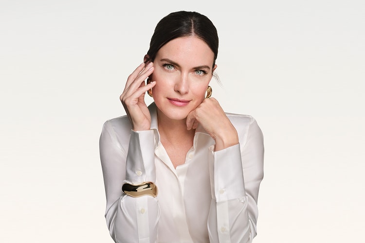 Frau mittleren Alters lächelt und stützt ihren Kopf auf der Hand ab