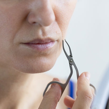 Frau entfernt ihre Gesichtsbehaarung in den Wechseljahren mit einer Pinzette