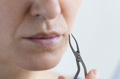 Frau entfernt ihre Gesichtsbehaarung in den Wechseljahren mit einer Pinzette