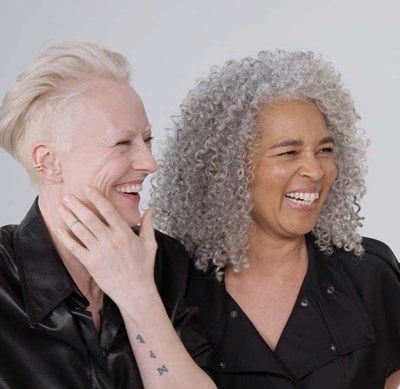 Vier Frauen lachen und lächeln fröhlich miteinander.