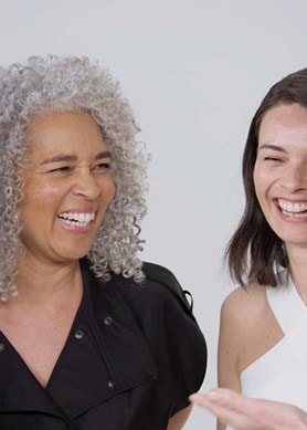 Vier Frauen lachen und lächeln fröhlich miteinander.