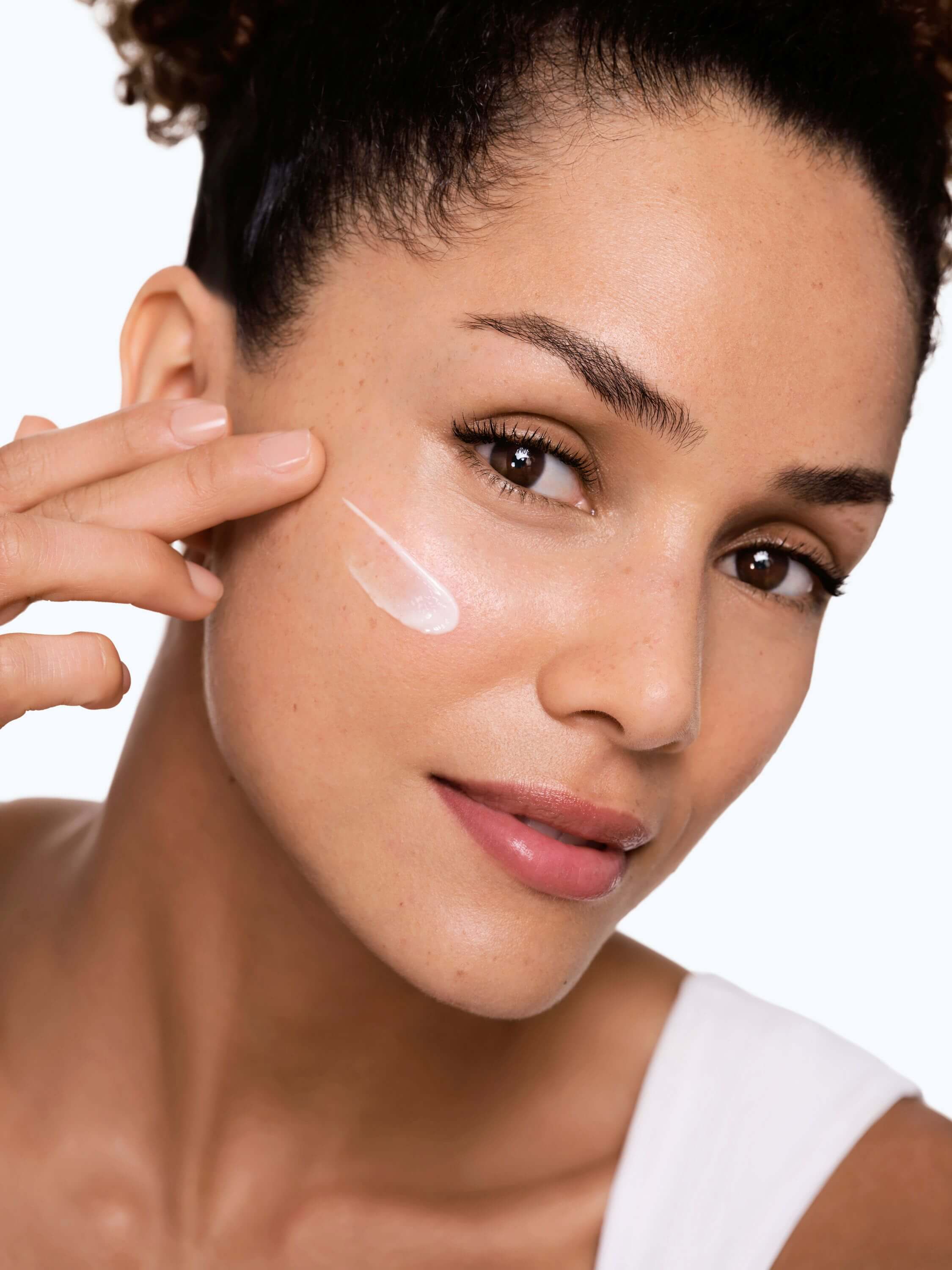 Frau verteilt Sonnencreme auf ihrer Wange