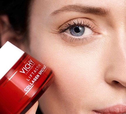 Nahaufnahme des Gesichts einer Frau welche Vichy Tagescreme neben ihrer Wange hält.