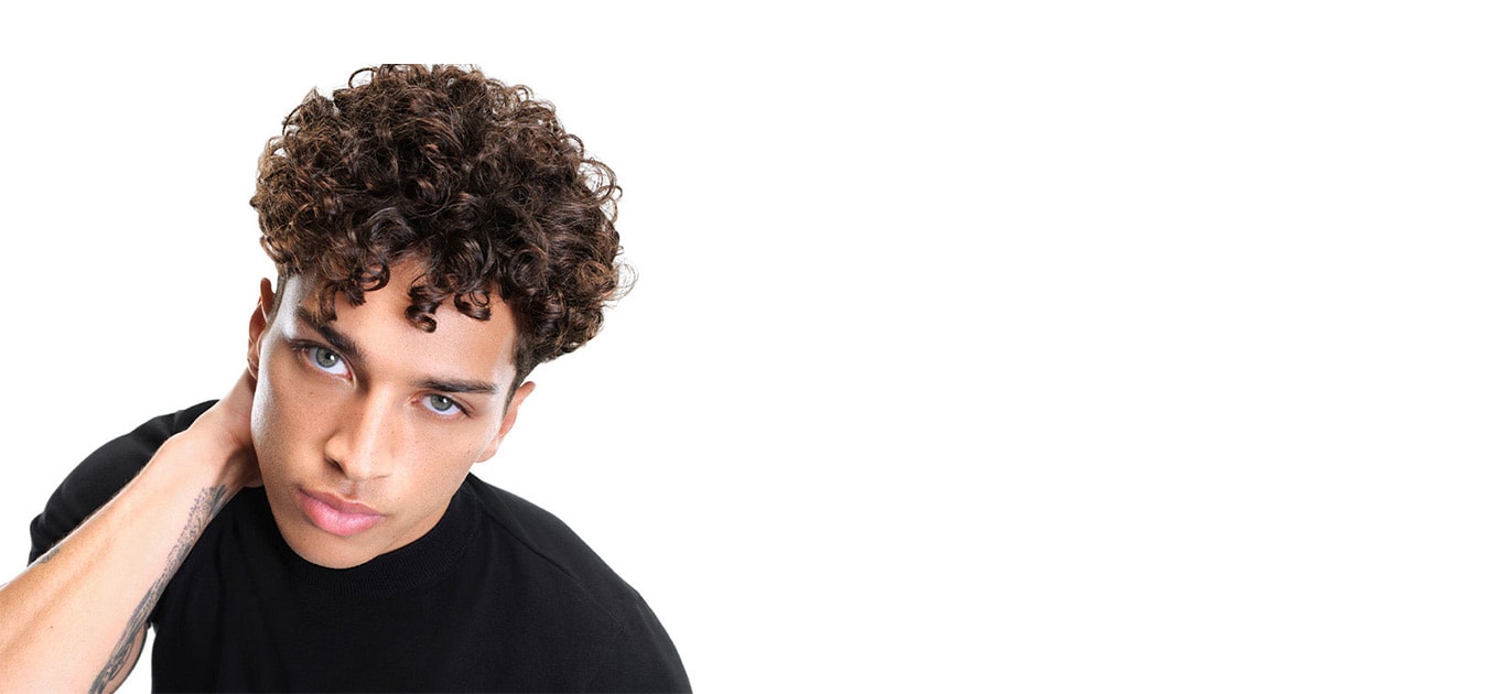 Männliches Model mit braunen Locken schaut frontal und greift sich in den Nacken