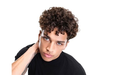 Männliches Model mit braunen Locken schaut frontal und greift sich in den Nacken