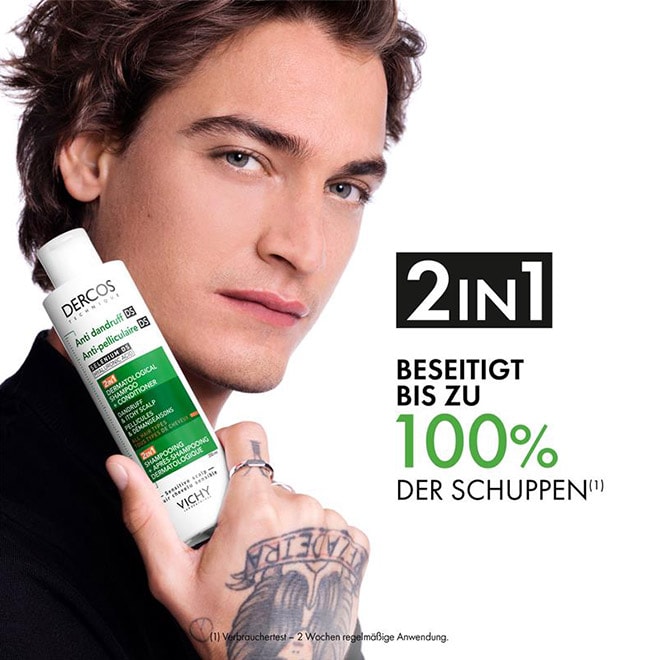 Person hält eine Flasche Vichy Dercos Anti-Schuppen 2-in-1 Shampoo in der Hand. Daneben steht der Text: ‚2 in 1 – Beseitigt bis zu 100 % der Schuppen‘