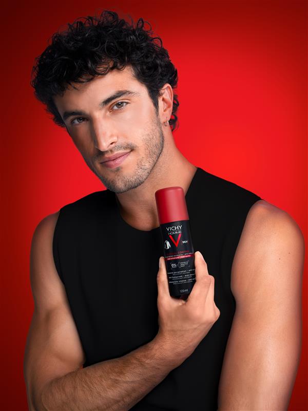 Mann in schwarzem Shirt hebt den Arm und hält ein Vichy Deodorant