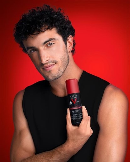 Mann in schwarzem Shirt hebt den Arm und hält ein Vichy Deodorant