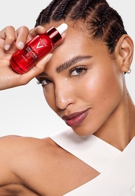 Frau hält Vichy Dercos-Serum-Flakon an ihre Stirn