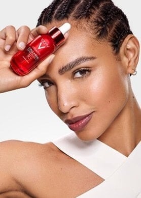 Frau hält Vichy Dercos-Serum-Flakon an ihre Stirn