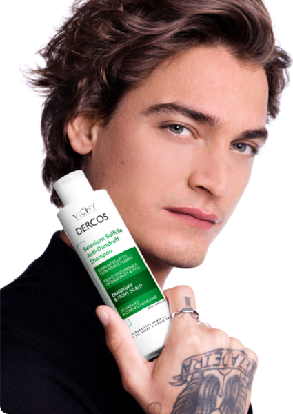 Junger Mann mit Vichy Dercos Anti-Schuppen Shampoo in der Hand