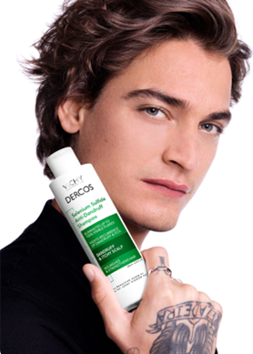 Junger Mann mit Vichy Dercos Anti-Schuppen Shampoo in der Hand