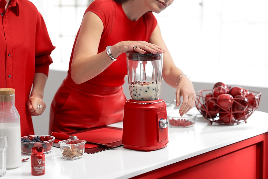 Nahaufnahme einer jungen Frau im roten Kleid, die einen Smoothie macht