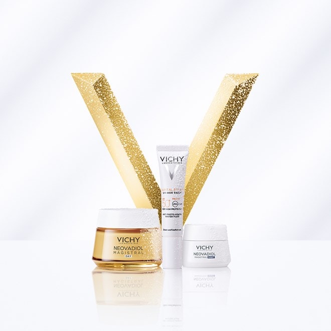Vichy-Produkte vor goldenem „V“-Dekor: Tagescreme, Sonnencreme und Nachtcreme, präsentiert auf weißem Hintergrund mit glitzernden Akzenten.