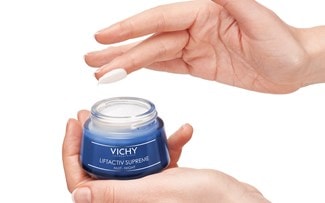 Hand hält LIFTACTIV SUPREME Nachtcreme und die andere Hand hat Klecks Creme am Finger