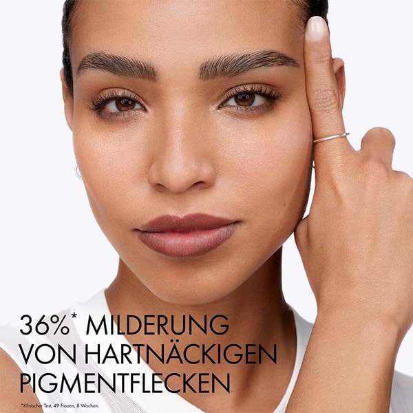 Frau mit ebenmäßigem Teint berührt ihre Schläfe, daneben Schriftzug „36 %* Milderung von hartnäckigen Pigmentflecken“