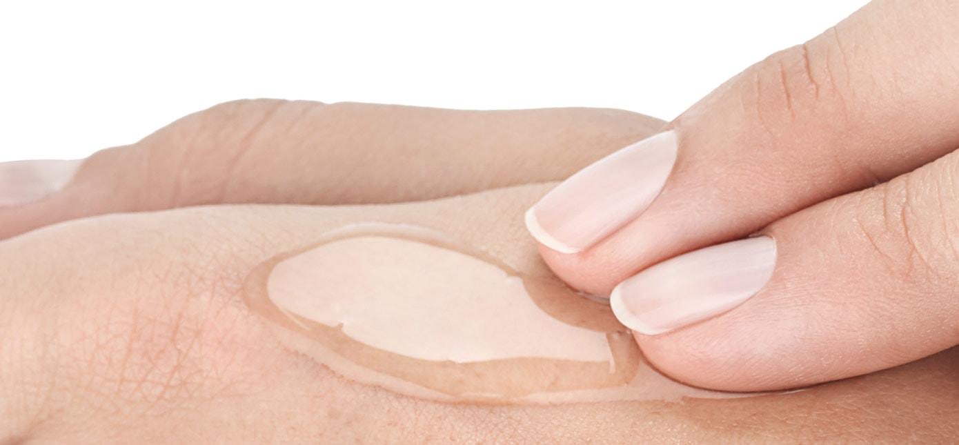 Zwei Finger verteilen ein durchsichtiges Gel auf einem Handrücken