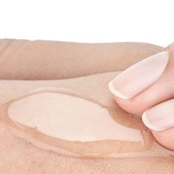 Zwei Finger verteilen ein durchsichtiges Gel auf einem Handrücken