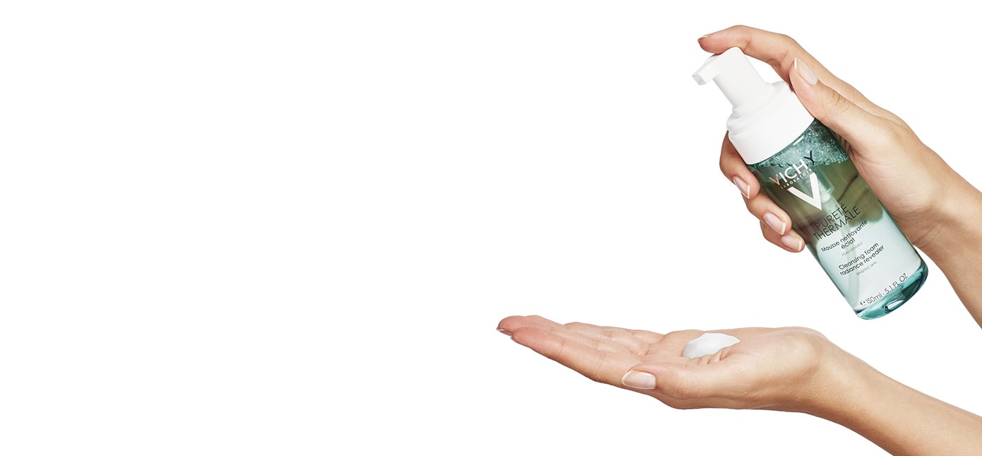 Person gibt sich PURETÉ THERMALE Reinigungsschaum auf die Handinnenfläche