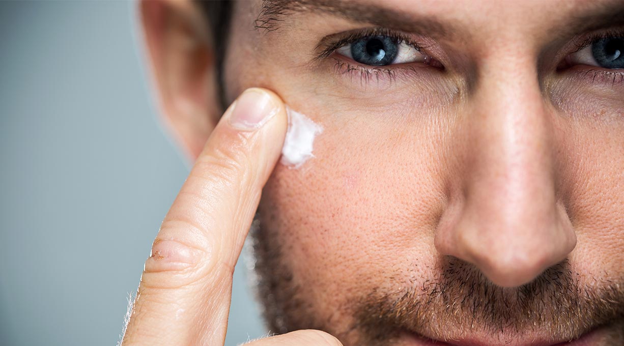Mann verteilt mit einem Finger Creme unter seinem Auge