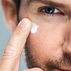 Mann verteilt mit einem Finger Creme unter seinem Auge