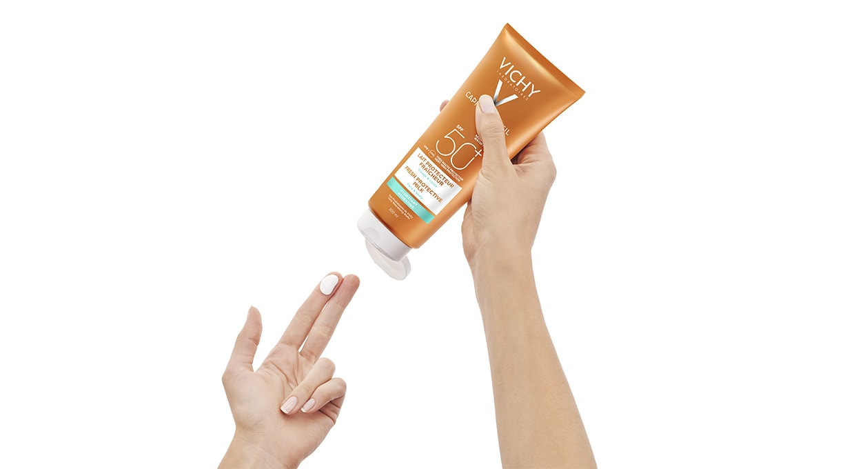 Person gibt einen Klecks Vichy Sonnencreme auf ihre Finger