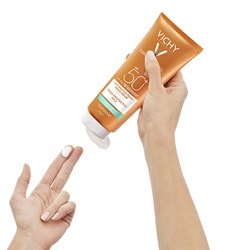 Person gibt einen Klecks Vichy Sonnencreme auf ihre Finger