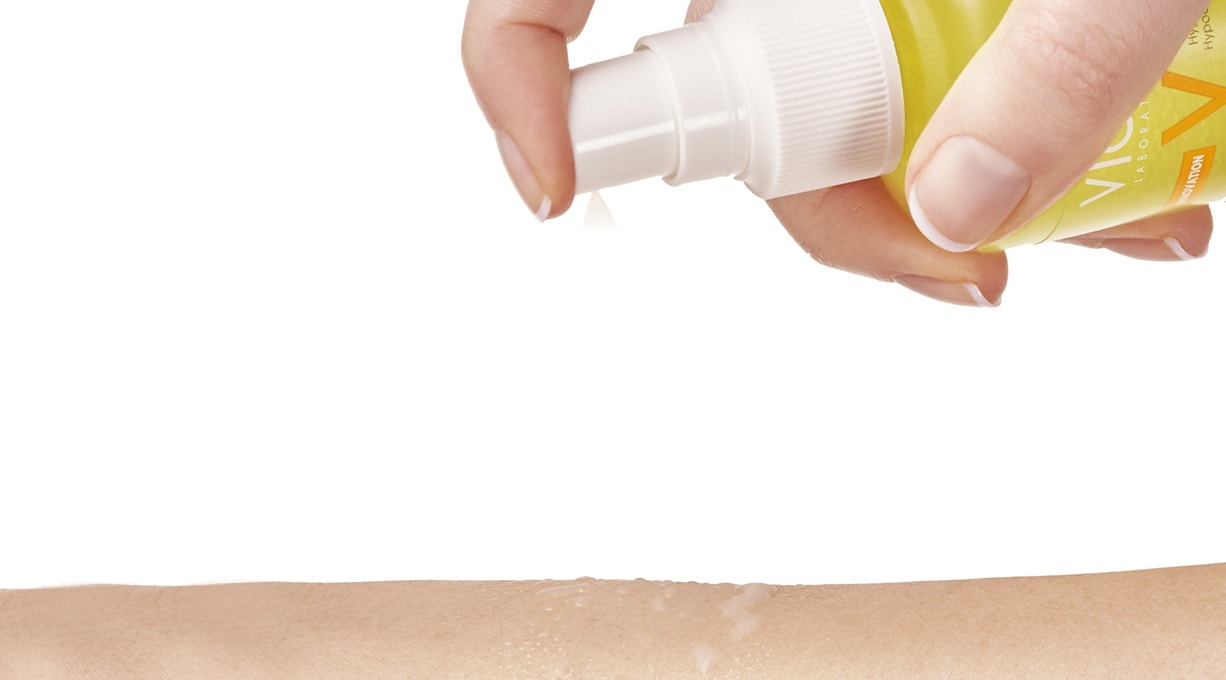 Person sprüht sich CAPITAL SOLEIL Sonnenspray auf den Arm